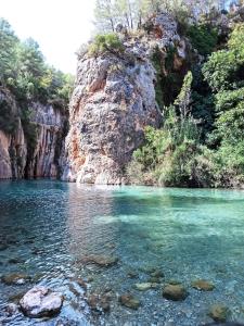 Un río con agua clara y un acantilado rocoso en Apartamento Montanejos en Montanejos