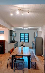 a kitchen with a wooden table with chairs and a refrigerator at Grand gîte au cœur des Pyrénées - Ariège Mijanes in Mijanès