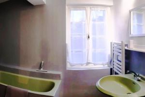 La salle de bains est pourvue d'un lavabo vert et d'une fenêtre. dans l'établissement Grand gîte au cœur des Pyrénées - Ariège Mijanes, à Mijanès