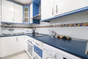 una cocina con armarios blancos y encimeras azules en La Casa Verde, en Almería