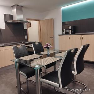 a dining room table with black chairs and a kitchen at Ferienwohnung Jessica in Mastershausen