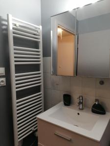 een badkamer met een witte wastafel en een spiegel bij La Galène chambre chez l'habitant in Illkirch-Graffenstaden