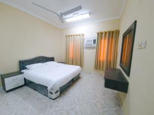a bedroom with a white bed and a table and curtains at أجاويد Ajaweed in Salalah