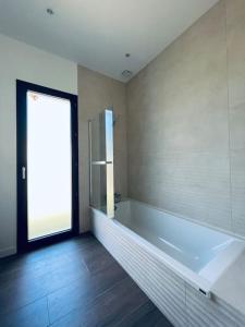 ein großes Badezimmer mit Badewanne und Fenster in der Unterkunft Villa Pura Vida in Magescq