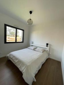 a bedroom with a large white bed with a window at Villa Pura Vida in Magescq