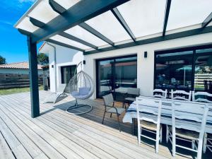 eine Holzterrasse mit einem Tisch und Stühlen darauf in der Unterkunft Villa Pura Vida in Magescq