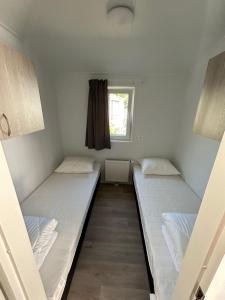 two beds in a small room with a window at Breezy Beach Chalet in Petten