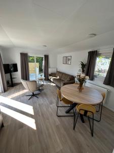 een woonkamer met een tafel en stoelen en een bank bij Breezy Beach Chalet in Petten