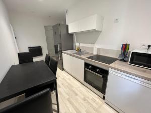 een keuken met witte kasten, een tafel en een magnetron bij Bel appartement Voiron centre in Voiron