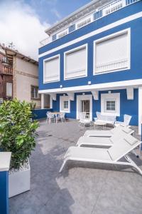 a blue building with chairs and tables in front of it at VILLA MARTA - Apartamentos céntricos junto al mar in Castro-Urdiales