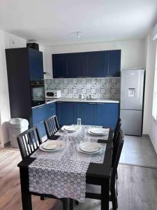 een keuken met een tafel met stoelen en blauwe kasten bij Bel appartement en centre-ville in Le Blanc-Mesnil