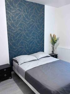 een slaapkamer met een bed met een blauwe muur bij Bel appartement en centre-ville in Le Blanc-Mesnil