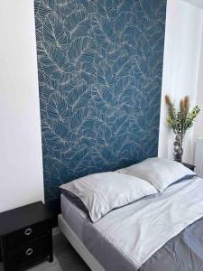 een bed in een slaapkamer met een blauwe muur bij Bel appartement en centre-ville in Le Blanc-Mesnil
