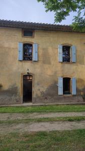 a building with three windows and a door and a building with a yard at Gîte à la campagne, proche Carcassonne in Alairac