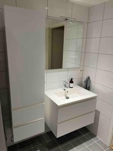 a white bathroom with a sink and a mirror at Leilighet ved sjøkanten in Langevåg