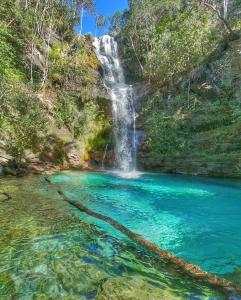 a waterfall in the middle of a pool of water at Chalé tribal in Alto Paraíso de Goiás