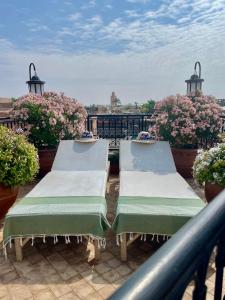 2 Liegestühle auf einem Balkon mit Blumen in der Unterkunft Riad Zouhour in Marrakesch
