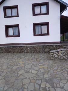 a white house with three windows and a stone patio at Nice view-Plitvice in Korenica