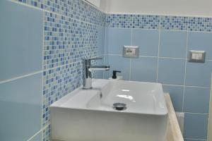 baño con lavabo blanco y azulejos azules en Arcu de Chelu B&B, en Modolo