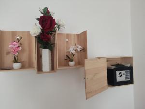 eine Reihe von Holzregalen mit Blumen und einer Uhr in der Unterkunft Tirano Express Apartments in Tirano
