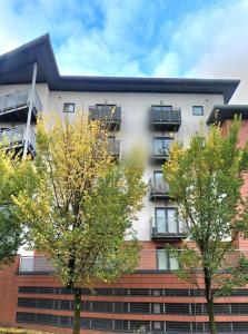 a tall white building with trees in front of it at Balcony-view with Free and secured Parking in Manchester