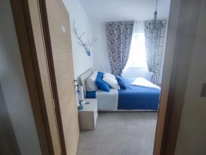 Schlafzimmer mit einem Bett mit blauer Bettwäsche und einem Fenster in der Unterkunft Tirano Express Apartments in Tirano