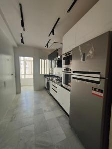 a large kitchen with white cabinets and appliances at Appartement meublé sala al jadida in Oulad Yakoub