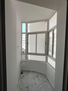 an empty room with two windows and a stone floor at Appartement meublé sala al jadida in Oulad Yakoub