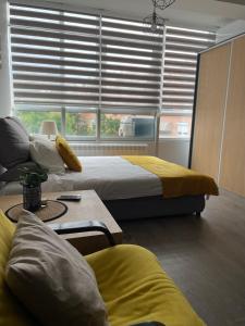- une chambre avec 2 lits, un canapé et une fenêtre dans l'établissement Kamche apartment, à Skopje