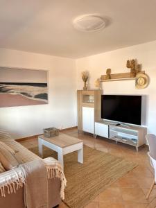 Villa Do Juano في لاجاريس: غرفة معيشة مع أريكة وتلفزيون