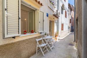 an alley with a table and chairs in a window at Kovacine apartment in Cres