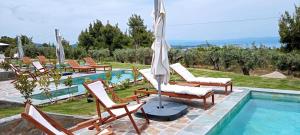 a group of chairs sitting next to a swimming pool at NOCE Luxury Villas Resort in Vourvourou
