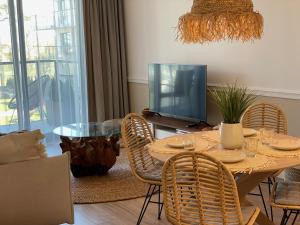 sala de estar con mesa con sillas y TV en Apartament PLAŻOWY 214 - Rezydencja Niechorze, en Niechorze