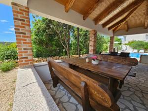 a patio with a wooden table and two benches at Holiday homes Sintija in Rab