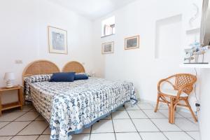 a white bedroom with a bed and a chair at Casa Zu Peppino in Lipari