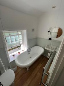 a white bath tub in a bathroom with a window at 2a Coastguard Cottages in Gorran Haven
