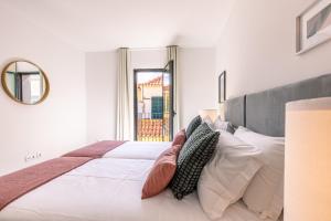 um quarto branco com uma cama grande e almofadas em Fort Bay Suite Apartments em Machico