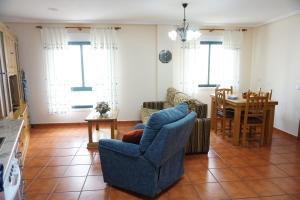 uma sala de estar com uma cadeira azul e uma mesa em Hermanas Iglesias em O Vicedo