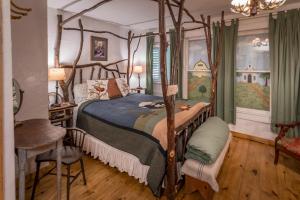 ein Schlafzimmer mit einem Himmelbett, einem Tisch und einem Stuhl in der Unterkunft Country Woods Inn in Glen Rose