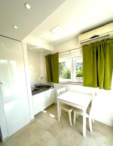 cocina con mesa blanca y cortinas verdes en Apartments Lomara, en Dubrovnik
