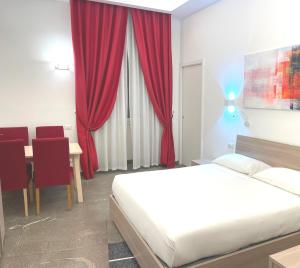 Schlafzimmer mit einem Bett, einem Tisch und roten Vorhängen in der Unterkunft Manfredi House San Pietro in Rom