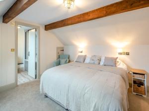 a bedroom with a large white bed and two blue chairs at The Stables Cottage in Hemingby