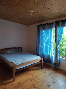a bedroom with a bed and a window with blue curtains at Departamentos Sato in Apóstoles