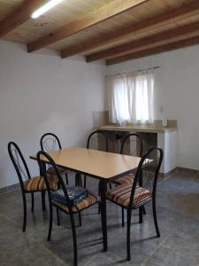 a dining room table with four chairs and a kitchen at Departamentos Sato in Apóstoles