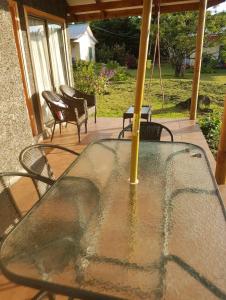 una mesa de cristal con sillas y una sombrilla en el patio en cabañas Honu iti, en Hanga Roa