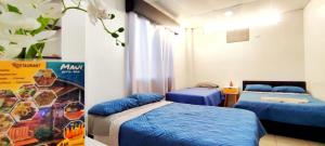 dwa łóżka w pokoju z niebieską pościelą w obiekcie Bahía Gardner w mieście Puerto Baquerizo Moreno