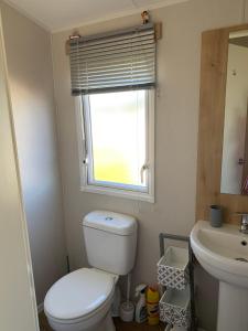 a bathroom with a toilet and a sink and a window at Bliss Beach Lodge in Bembridge