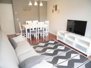 een woonkamer met een bank, een tv en een tafel bij Concheira Deluxe, precioso apartamento in Baiona