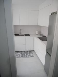 een keuken met witte kasten, een wastafel en een vloer bij Concheira Deluxe, precioso apartamento in Baiona