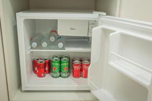 an open refrigerator with cans of soda in it at Chalé Mantiqueira - Cunha in Cunha